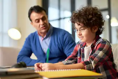 Une lycéenne concentrée étudiant avec sa camarade de classe à côté d'elle, illustrant l'entraide et la concentration dans les études.